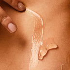 Close-up of a hand applying a beige-colored lotion or cream onto skin.