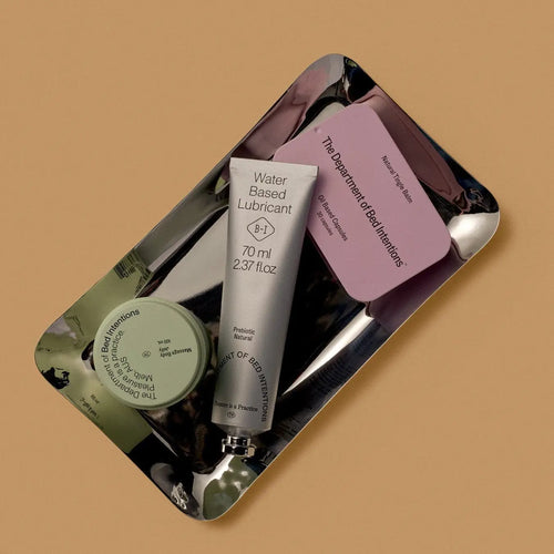 Set of personal care products on a reflective surface with a beige background