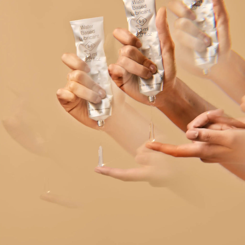 Hands holding and using water-based lubricant on a beige background