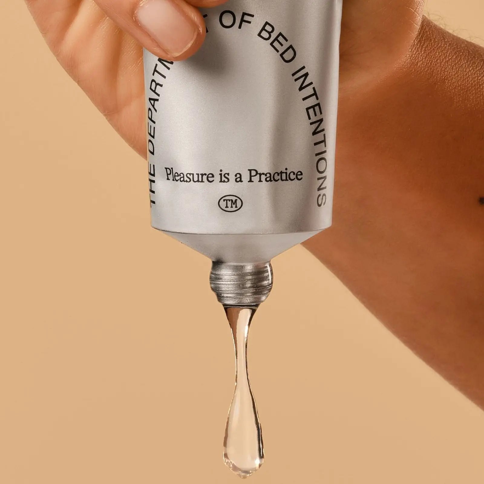 Skincare serum dropper with 'The Department of Bed Intentions' branding on a beige background