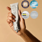Hand holding a tube of water-based lubricant with awards displayed on a beige background