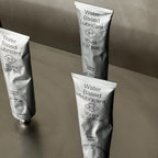 Three tubes of water-based lubricant on a reflective surface with a neutral background