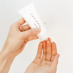 Hand holding a white container labeled 'COCONUT' against a light background