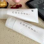 Two COCONU products on a textured surface with a phone and snacks in the background.