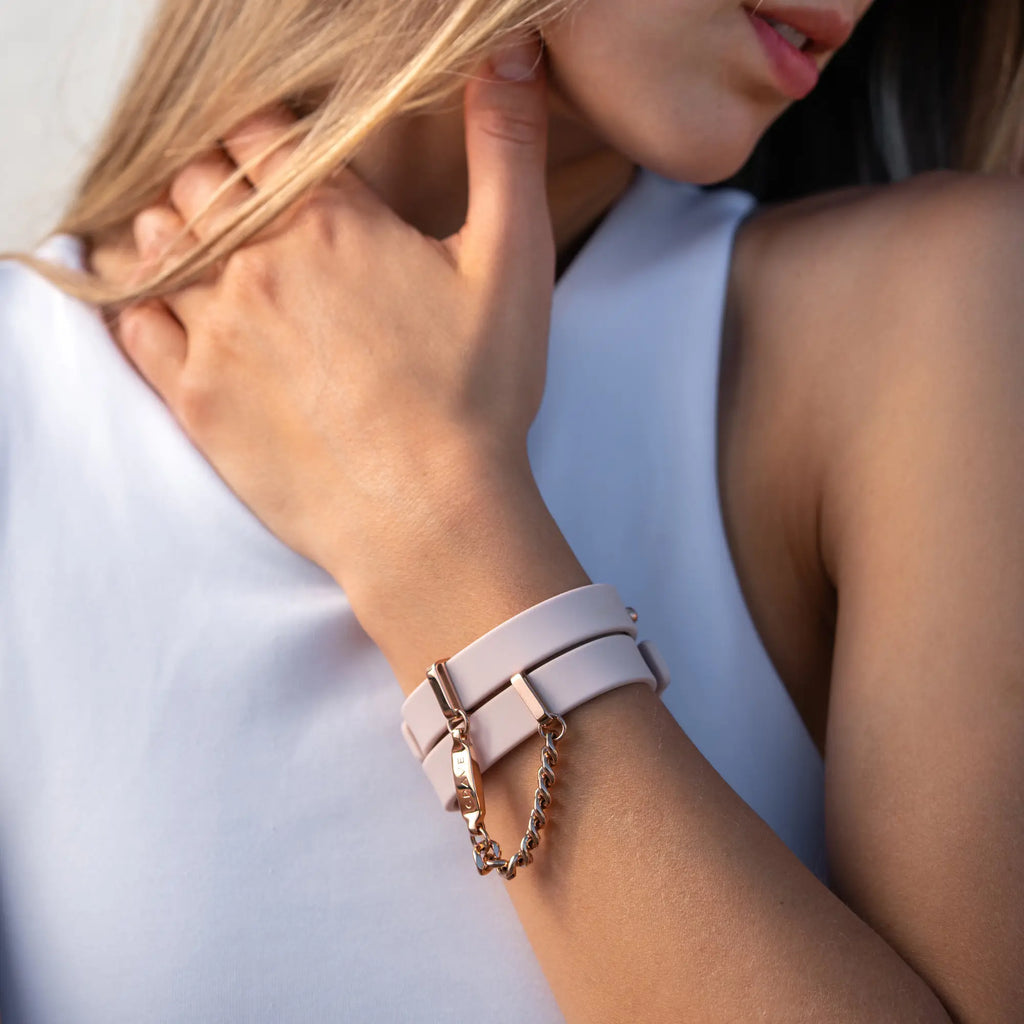 Close-up of a person wearing a pink bracelet with a chain detail on a light background
