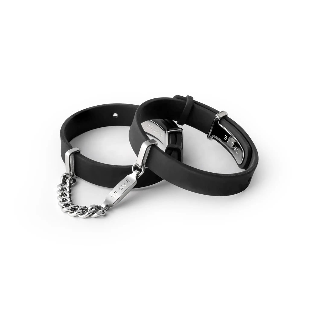 Two black rubber bracelets with silver chains on a white background
