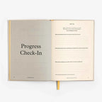Open book with 'Progress Check-In' on a white background
