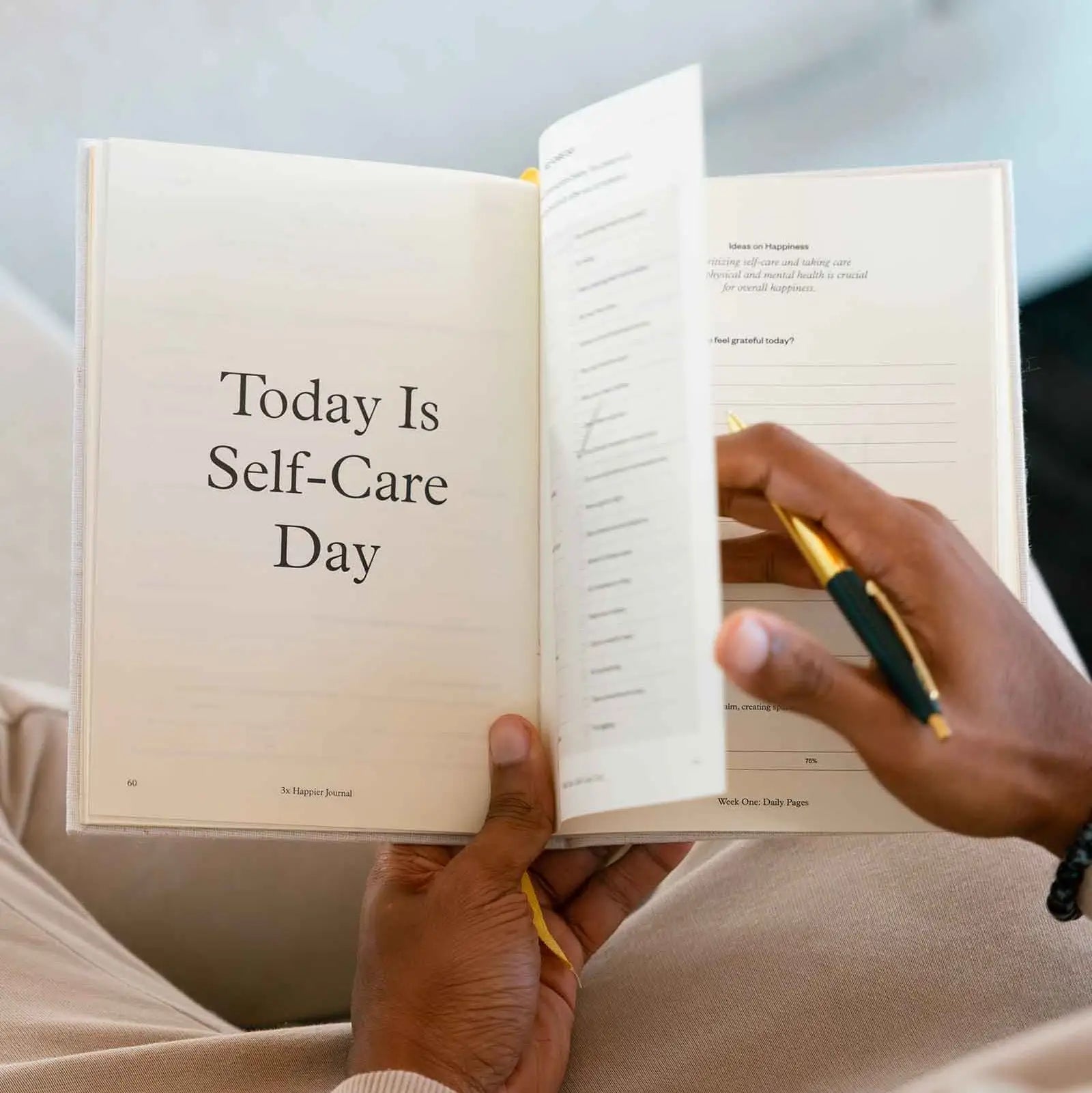 Person holding a book titled 'Today Is Self-Care Day' with a pen.