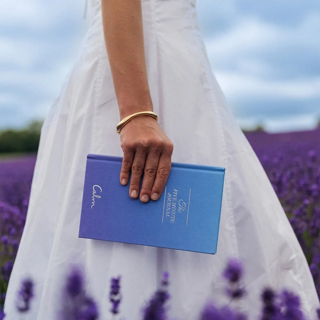 Person holding a blue book with a lavender field in the background