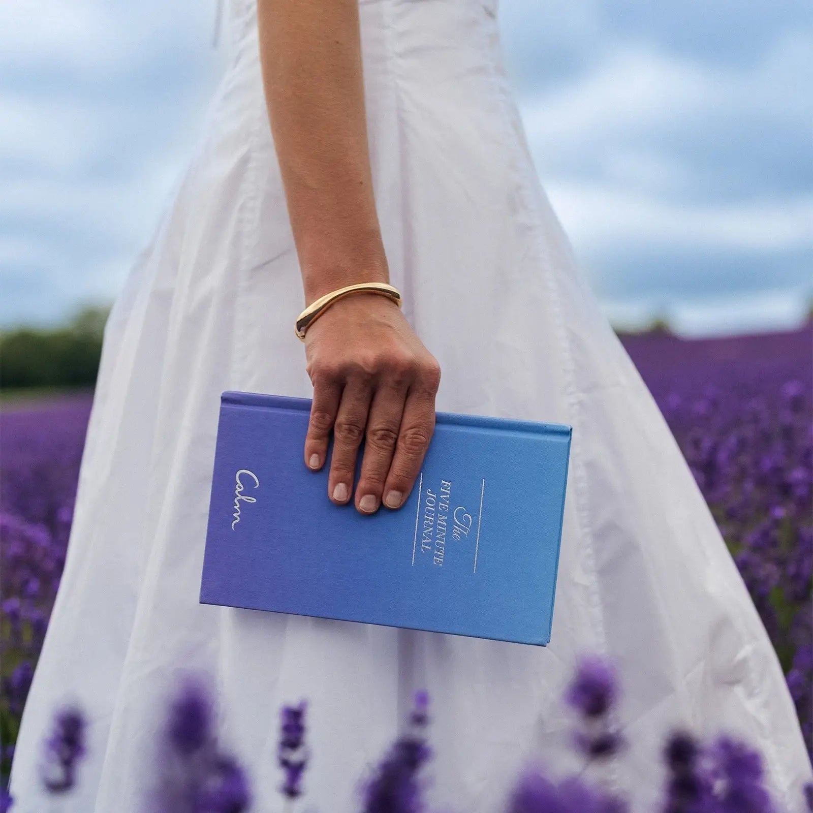 Person holding a blue book with a lavender field in the background