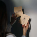 Person holding two cards with text and a logo, against a neutral background
