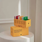 Yellow boxes with colorful cards on a white pedestal against a neutral wall.