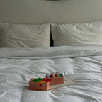 Colorful toy on a white bed with a textured headboard