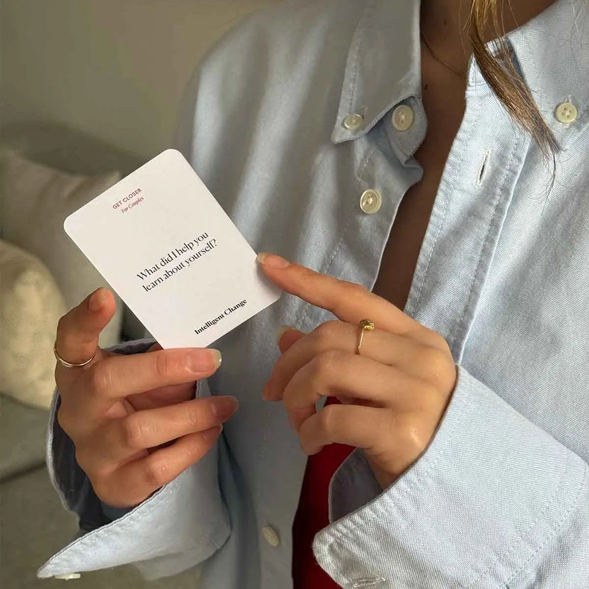 Person holding a card with text, wearing a light blue shirt indoors.