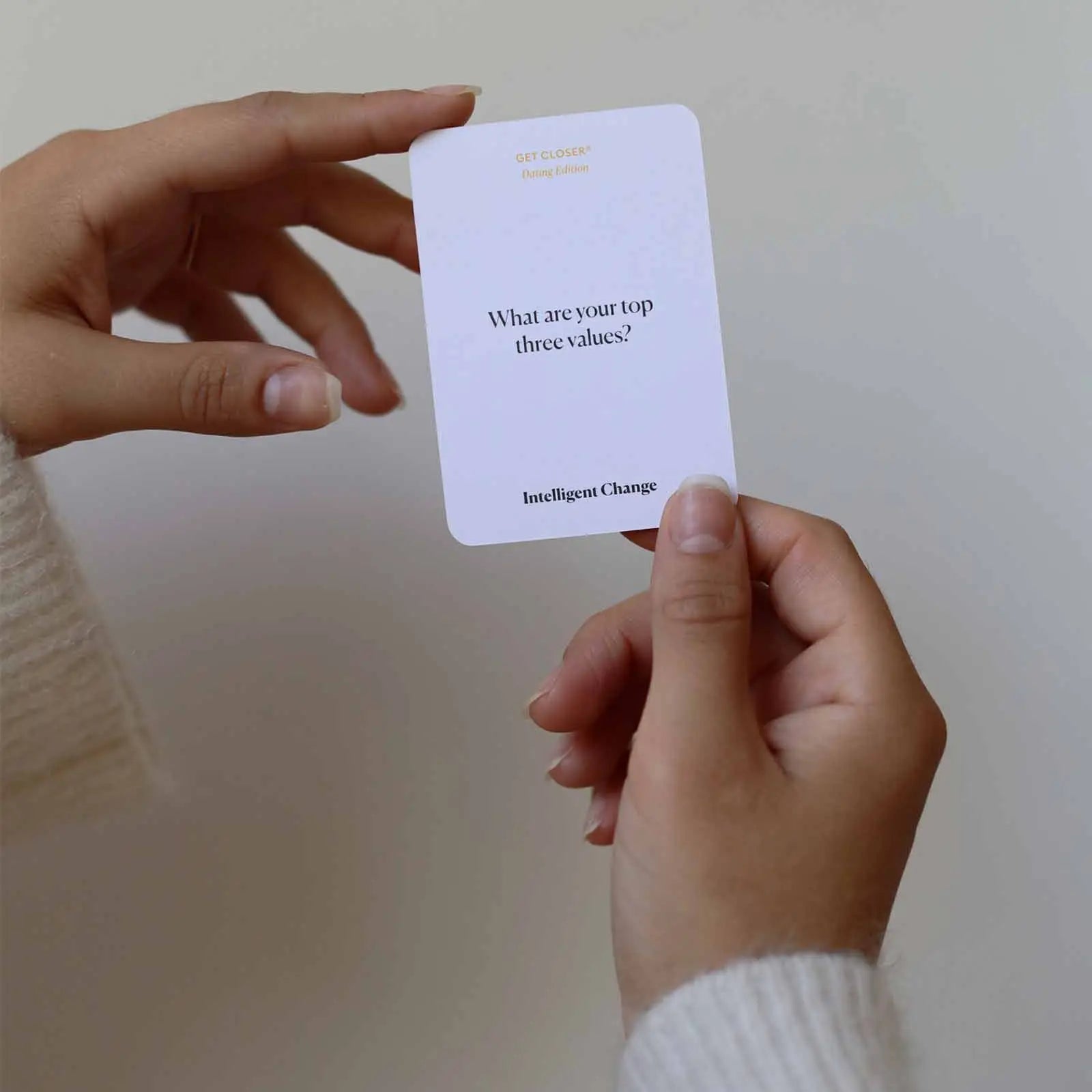Hand holding a card with 'What are your top three values?' question on a plain background