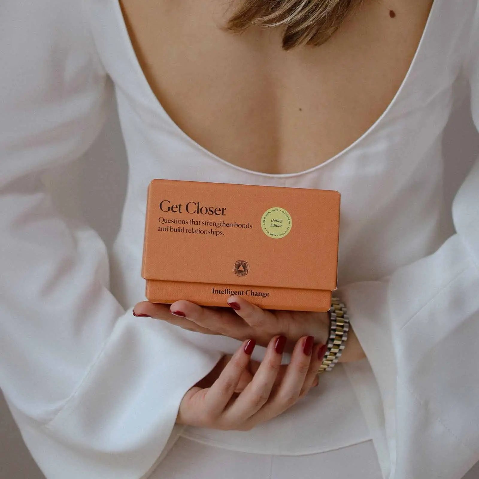 Person holding an orange product box labeled 'Get Closer' with a white background