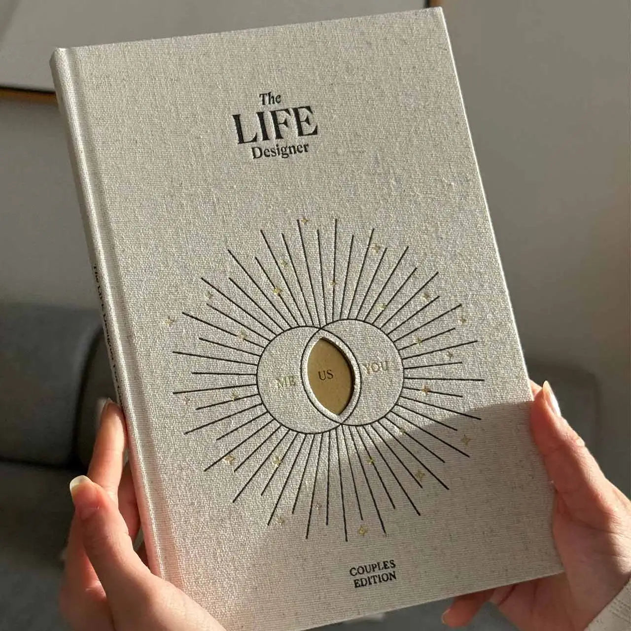 Book titled 'The LIFE Designer' held by a person with a neutral background