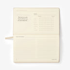  cream colored planner with a calendar and lined pages on a white background