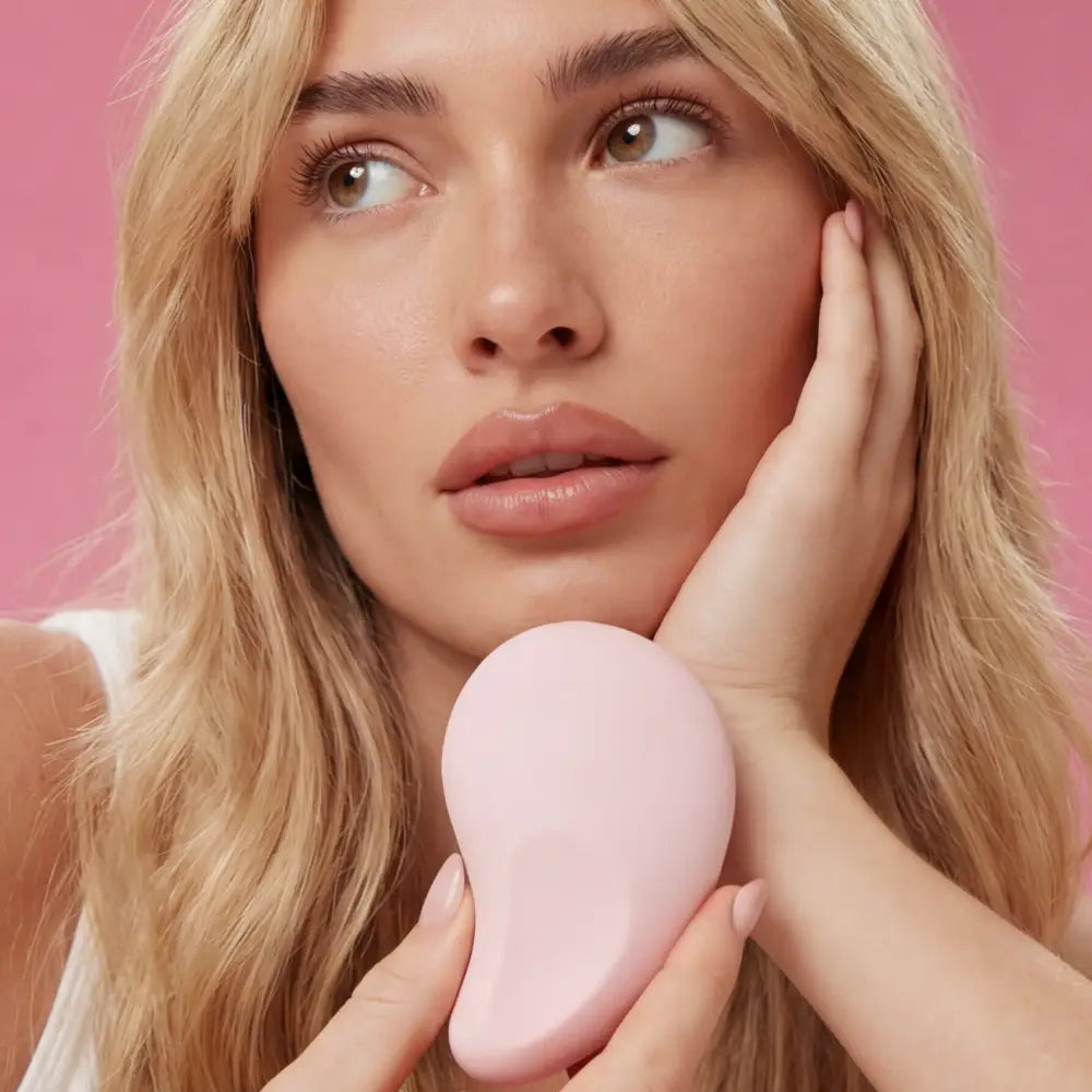 Woman holding a pink handheld device against a pink background