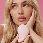 Woman holding a pink handheld device against a pink background