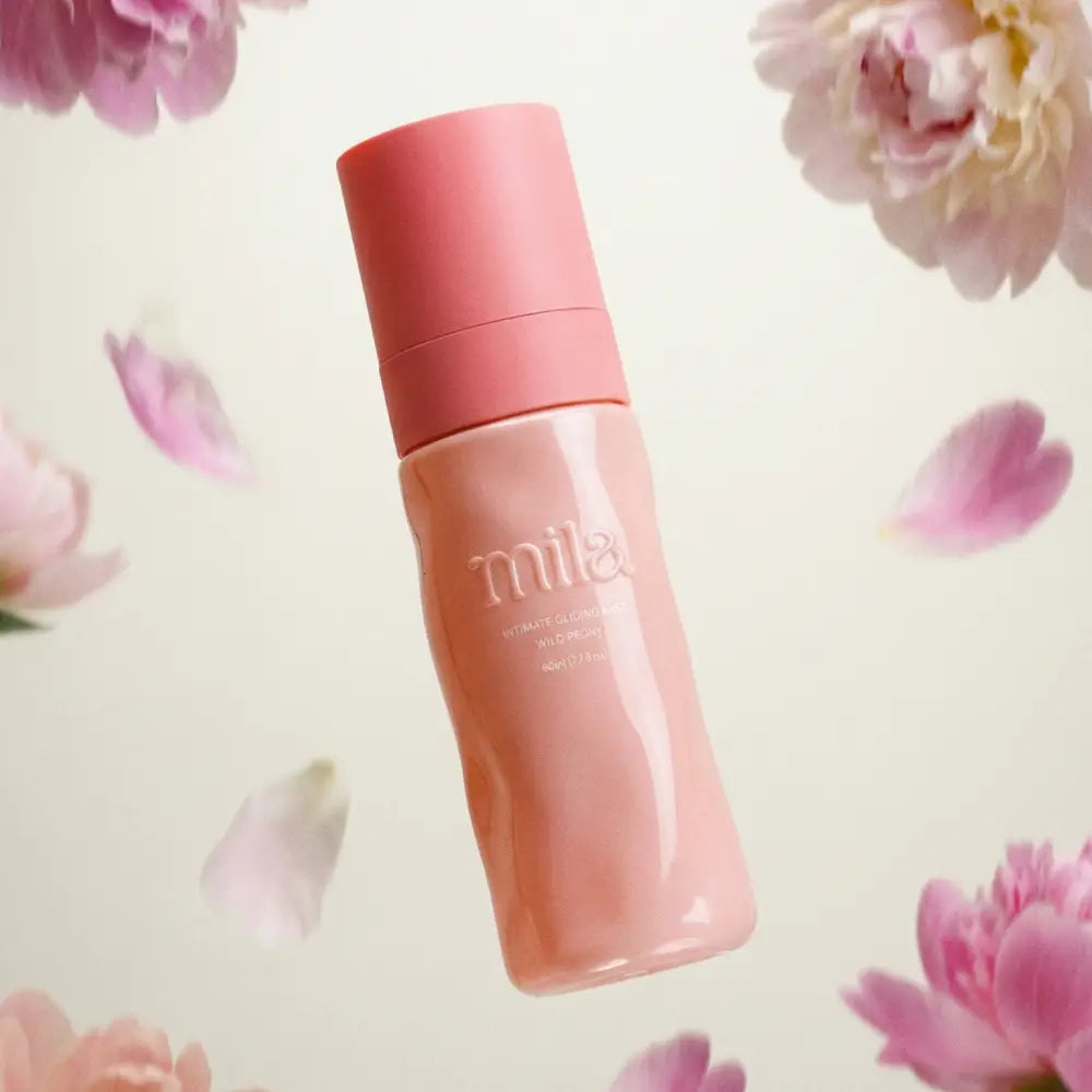 Pink bottle labeled 'milk' surrounded by pink flowers on a light background