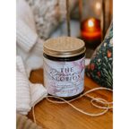 Candle labeled 'The Romance Section' on a wooden surface with soft lighting