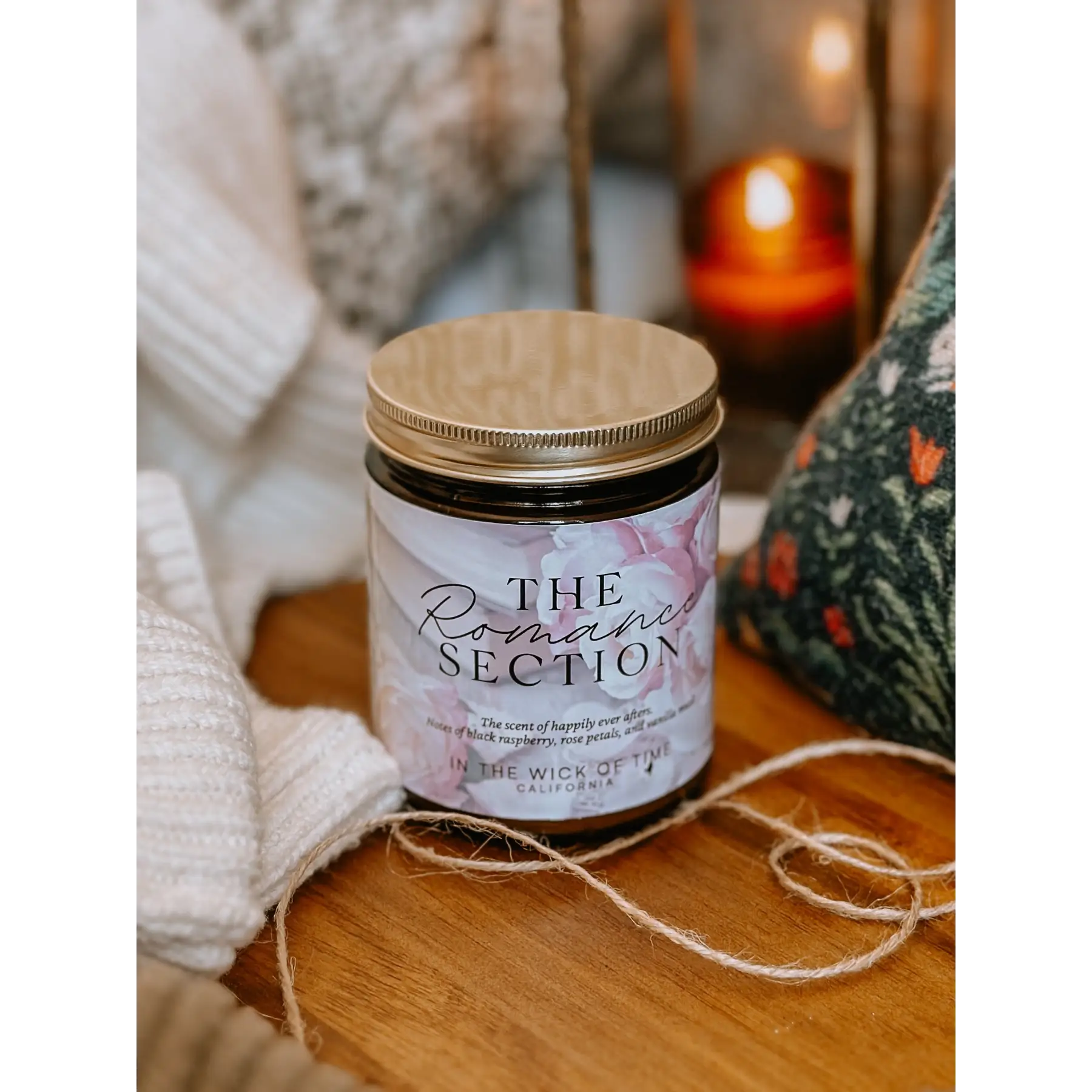 Candle labeled 'The Romance Section' on a wooden surface with soft lighting