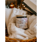 Candle labeled 'The Romance Section' in a basket with soft textures and warm tones