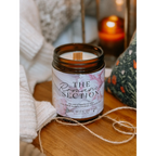 Candle labeled 'The Romance Section' on a wooden surface with soft lighting