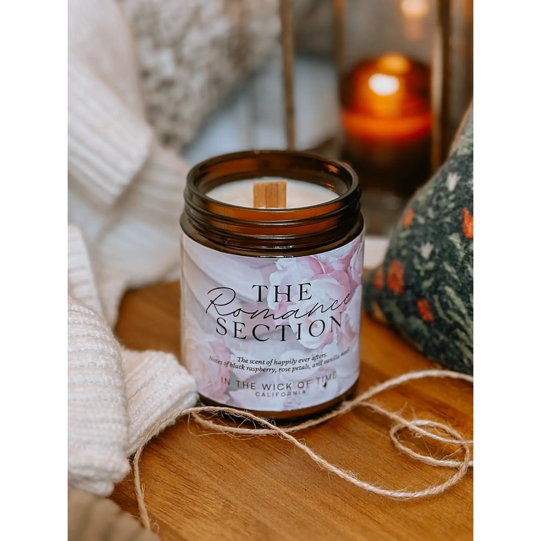 Candle labeled 'The Romance Section' on a wooden surface with soft lighting