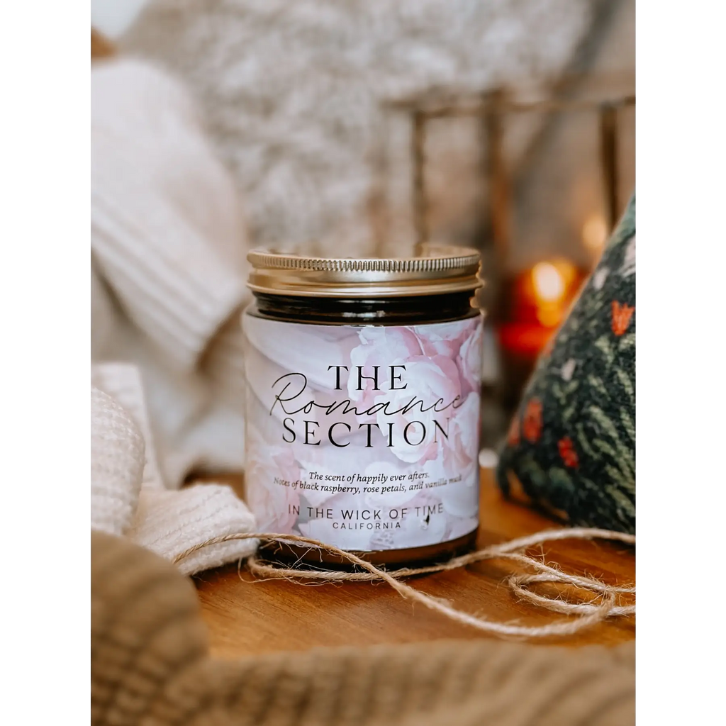 Candle labeled 'The Romantic Section' on a wooden surface with soft lighting