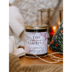 Candle labeled 'The Romantic Section' on a wooden surface with soft lighting