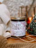 Candle labeled 'The Romantic Section' on a wooden surface with soft lighting